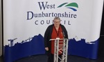 Woman standing on stage in front of West Dunbartonshire Council logo