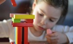 Girl playing and learning with building blocks at school