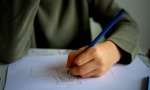 Young person drawing a tractor with a pencil on a A4 piece of paper