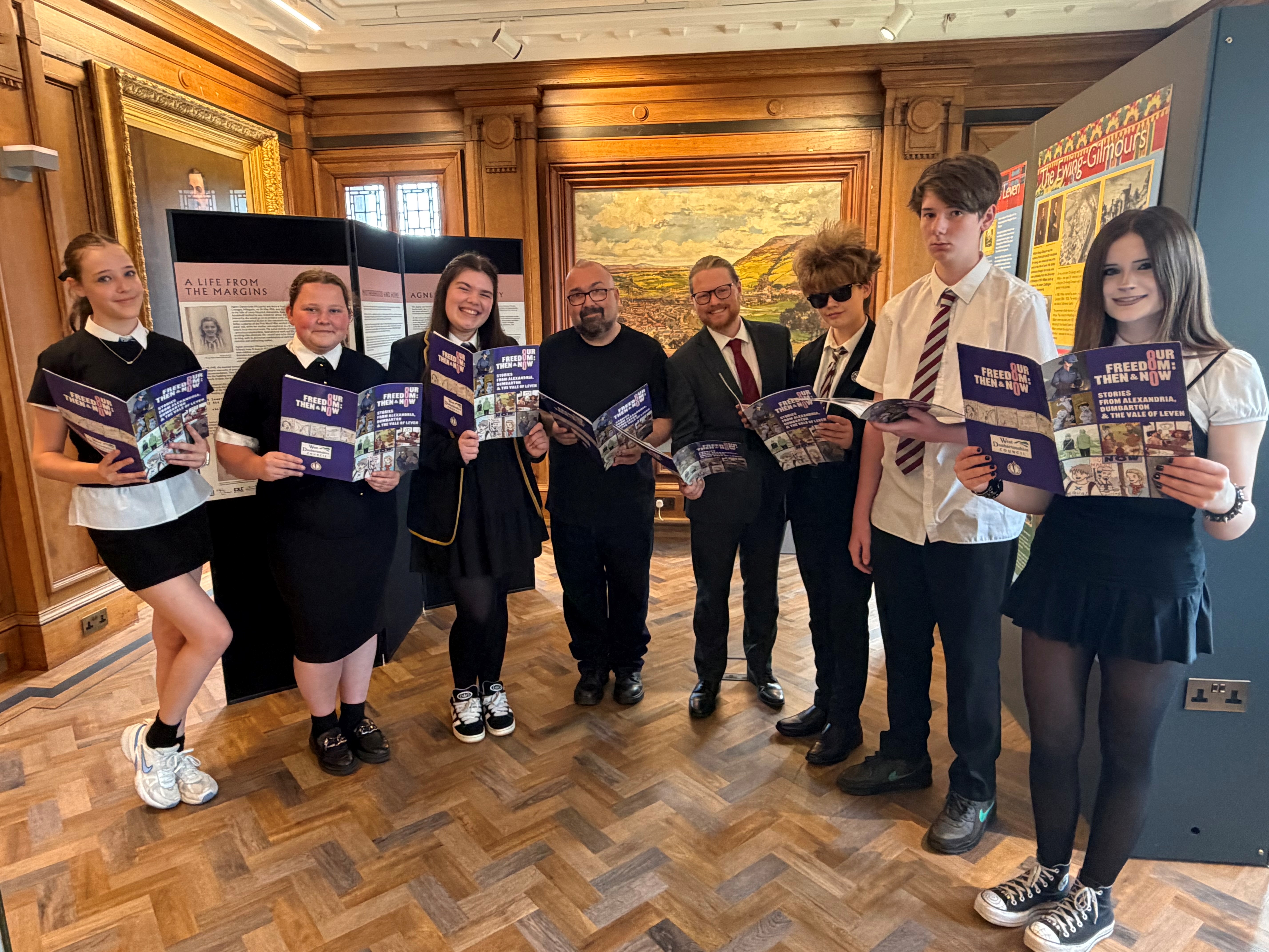 Cllr Rooney with pupils and author, holding up graphic novel