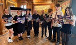 Cllr Rooney with pupils and author, holding up graphic novel