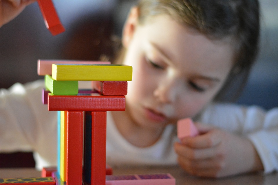 Young person building a tower with coloured wooden building blocks